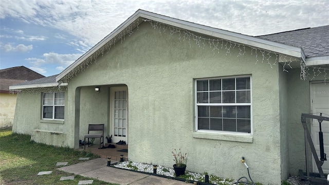 back of property with stucco siding and roof with shingles