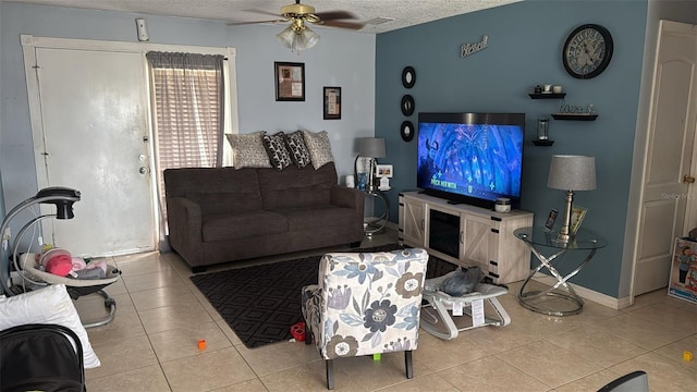 living room featuring a textured ceiling, ceiling fan, light tile patterned floors, and baseboards