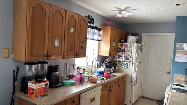 kitchen featuring brown cabinets, light countertops, a sink, a textured ceiling, and white appliances