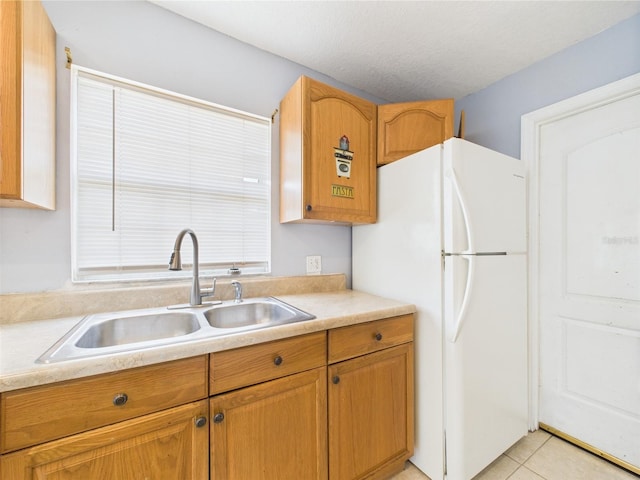 91 W Cedarwood Cir, Kissimmee, FL 34743 - kitchen featuring a sink, freestanding refrigerator, light countertops, light tile patterned floors, and brown cabinetry