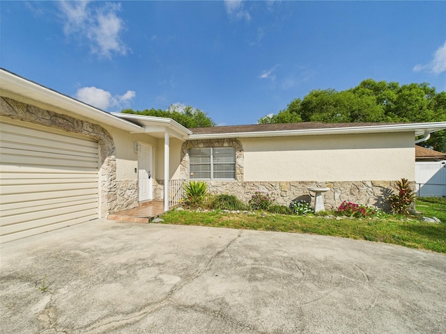 2434 Mill Run Blvd, Kissimmee, FL 34744 - view of home's exterior featuring stone siding, stucco siding, an attached garage, and fence