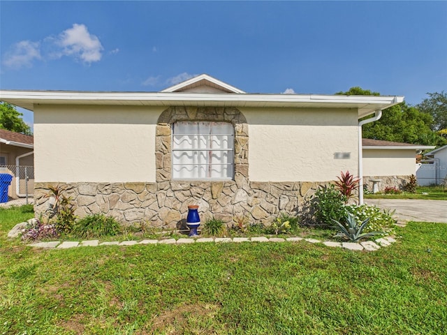 2434 Mill Run Blvd, Kissimmee, FL 34744 - view of home's exterior featuring stucco siding, stone siding, and a lawn