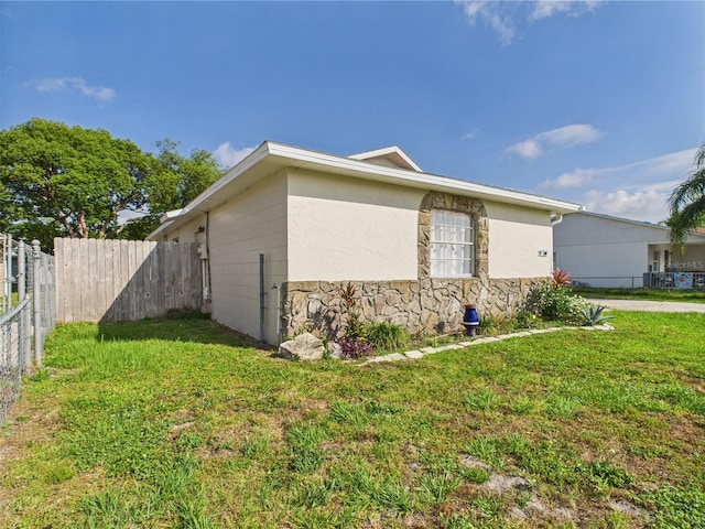 2434 Mill Run Blvd, Kissimmee, FL 34744 - view of side of home with a lawn, stone siding, and fence