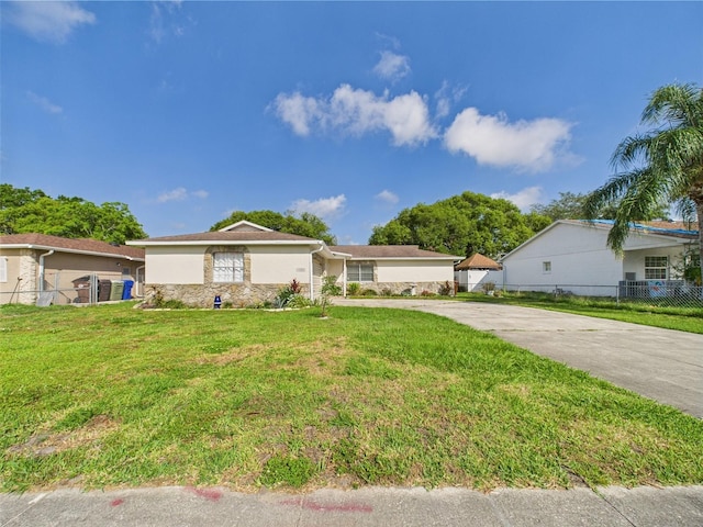 2434 Mill Run Blvd, Kissimmee, FL 34744 - ranch-style house with stone siding, stucco siding, fence, a front lawn, and driveway