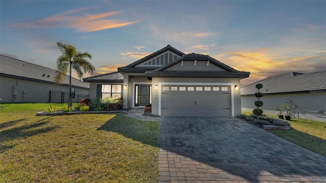 view of front of home with a garage, stucco siding, decorative driveway, and a yard