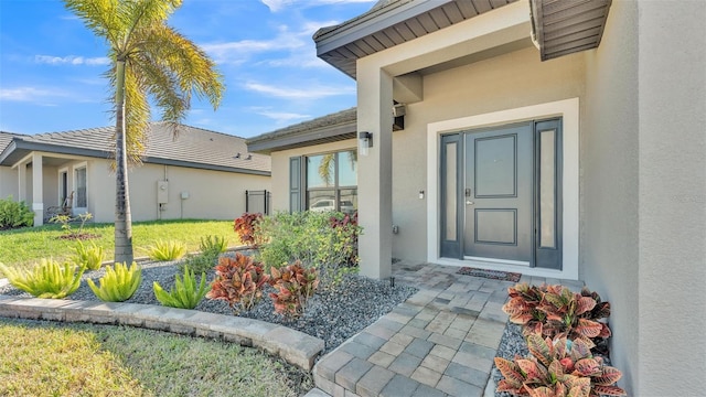 entrance to property with a lawn and stucco siding