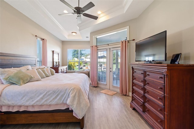 bedroom featuring french doors, crown molding, a raised ceiling, light wood-style floors, and access to outside