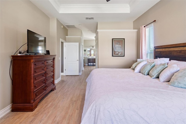 bedroom featuring light wood finished floors, a raised ceiling, visible vents, and baseboards