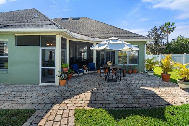 back of property featuring a patio area, a shingled roof, fence, and a sunroom