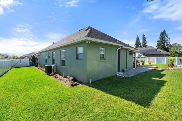 back of house with cooling unit, a fenced backyard, a yard, and stucco siding