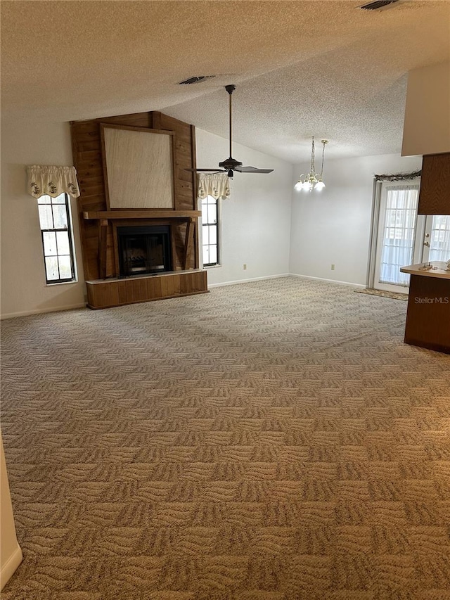 unfurnished living room with visible vents, a tile fireplace, lofted ceiling, a textured ceiling, and carpet flooring