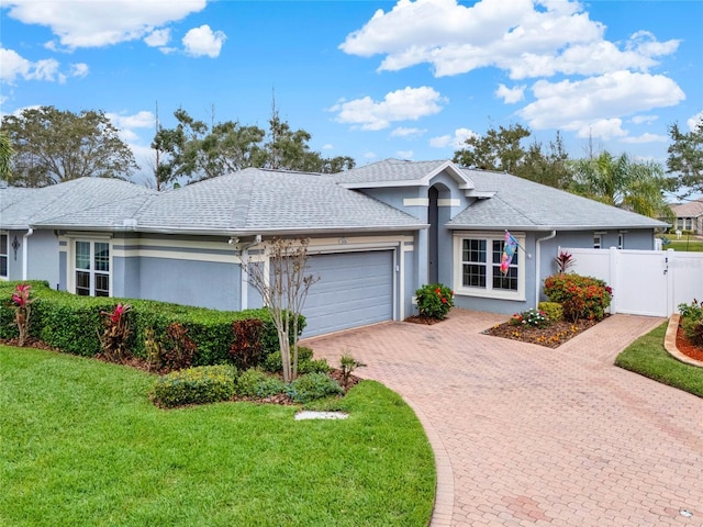 single story home with a garage, fence, decorative driveway, stucco siding, and a front lawn