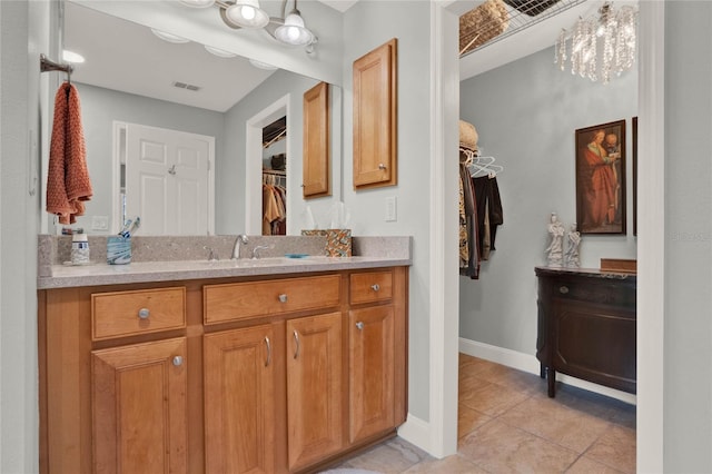 bathroom featuring baseboards, visible vents, tile patterned flooring, a spacious closet, and vanity