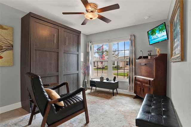 sitting room featuring a ceiling fan and baseboards