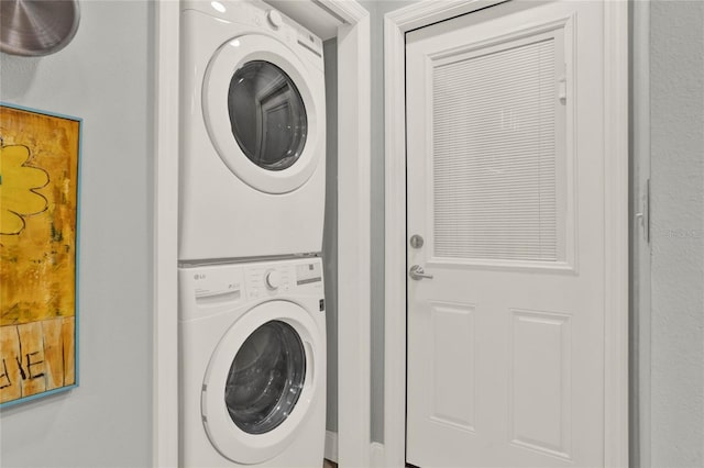 washroom featuring stacked washer and clothes dryer and laundry area