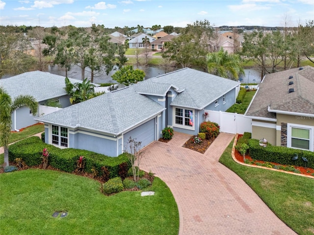 view of front of home with decorative driveway, roof with shingles, an attached garage, a front yard, and a residential view