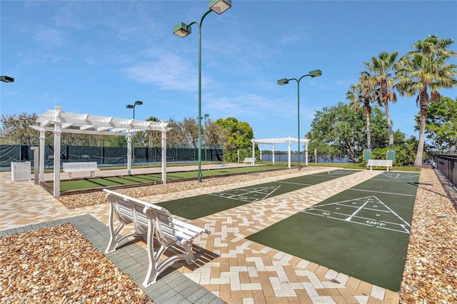 view of community with shuffleboard, fence, and a pergola