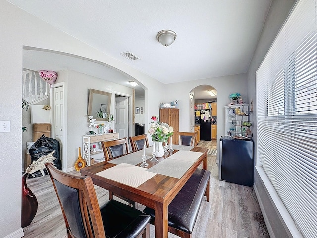 dining area with visible vents, arched walkways, and wood finished floors