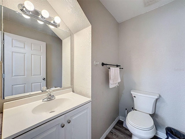 bathroom with baseboards, visible vents, toilet, wood finished floors, and vanity