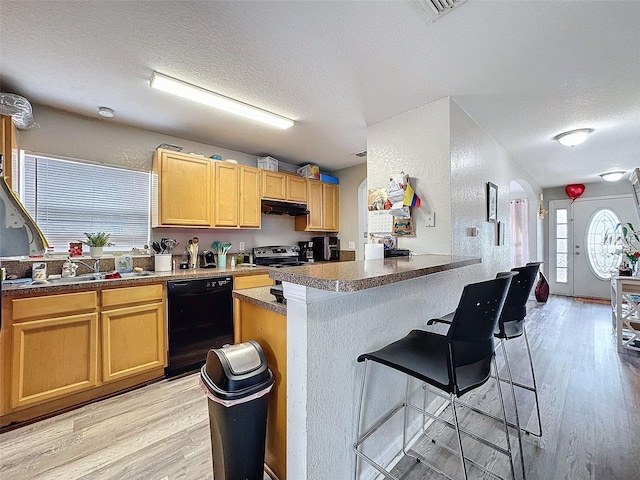 kitchen featuring dishwasher, dark countertops, a kitchen breakfast bar, a textured ceiling, and under cabinet range hood