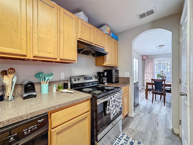 kitchen featuring arched walkways, light countertops, visible vents, stainless steel range with electric stovetop, and under cabinet range hood