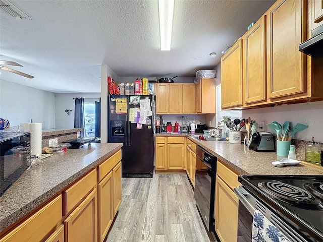 kitchen featuring under cabinet range hood, a textured ceiling, light wood-type flooring, black appliances, and a sink