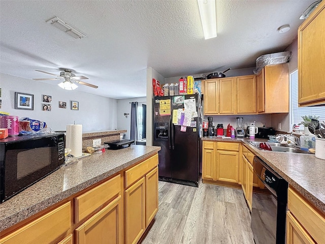 kitchen featuring a textured ceiling, light wood-style flooring, a sink, visible vents, and black appliances