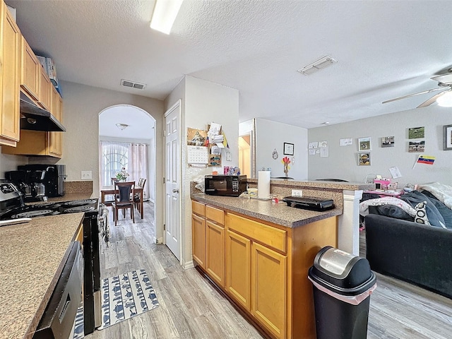 kitchen with under cabinet range hood, visible vents, arched walkways, and open floor plan