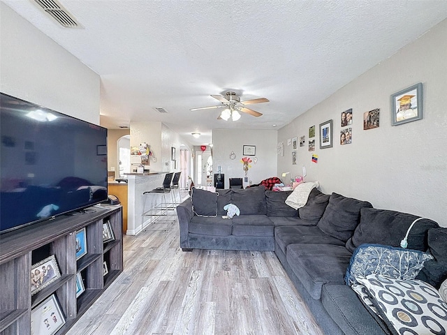 living room with visible vents, a textured ceiling, and light wood-style flooring