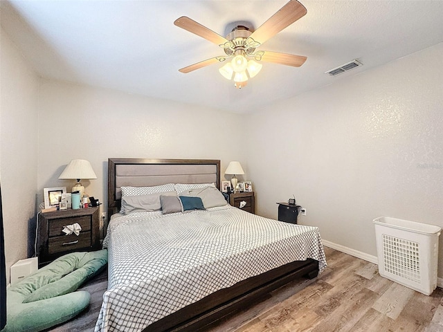 bedroom with light wood-style floors, baseboards, visible vents, and ceiling fan