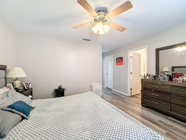 bedroom with light wood finished floors, ceiling fan, and visible vents