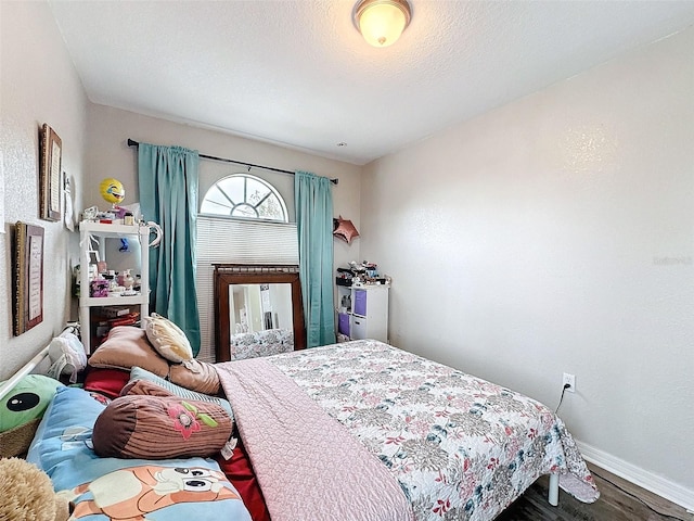 bedroom featuring a textured ceiling, wood finished floors, and baseboards