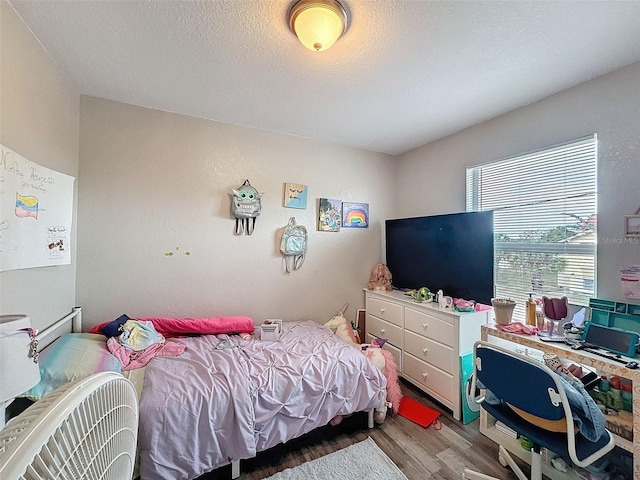 bedroom with a textured ceiling and wood finished floors