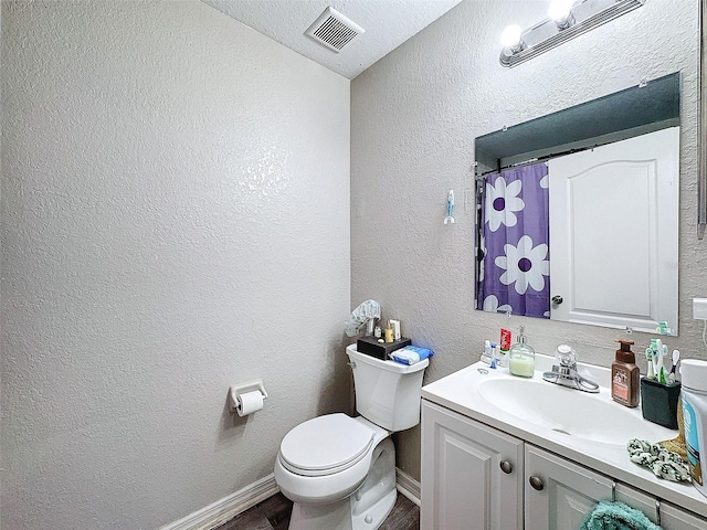 full bath with baseboards, visible vents, a textured wall, toilet, and vanity