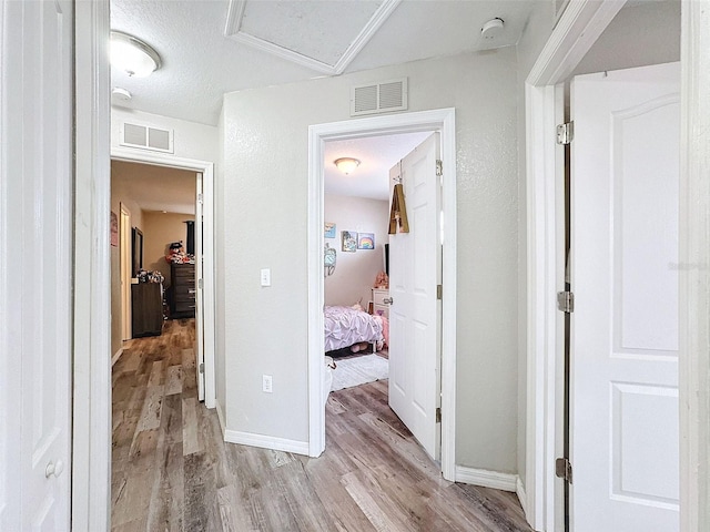 hall with light wood-style floors, baseboards, and visible vents