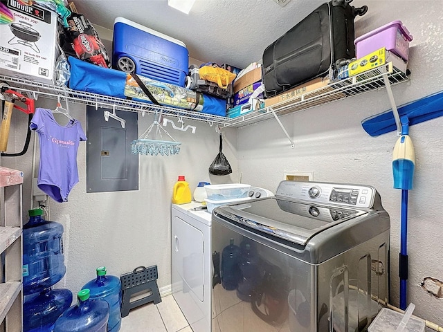 laundry area with light tile patterned floors, a textured ceiling, laundry area, electric panel, and washing machine and clothes dryer