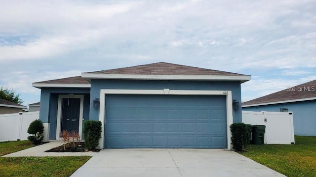 ranch-style house featuring an attached garage, fence, concrete driveway, stucco siding, and a front yard