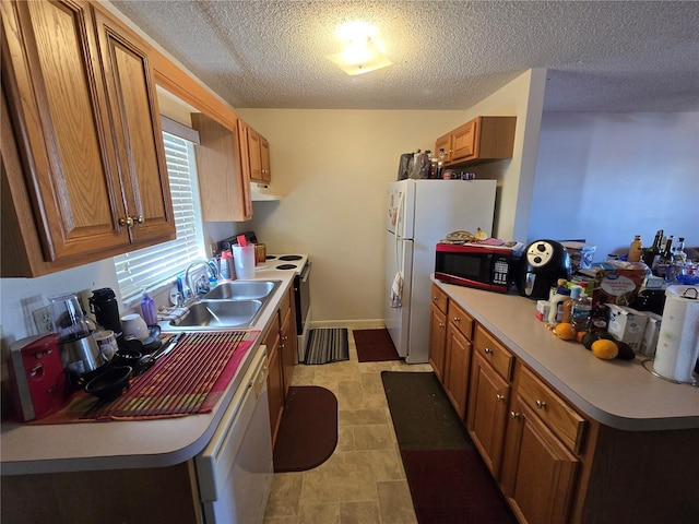 kitchen featuring white appliances, brown cabinets, light countertops, a textured ceiling, and a sink