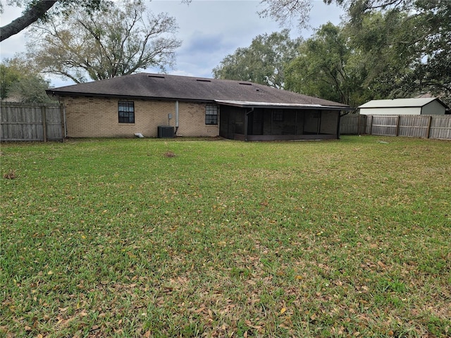 rear view of property with brick siding, a lawn, a sunroom, cooling unit, and a fenced backyard