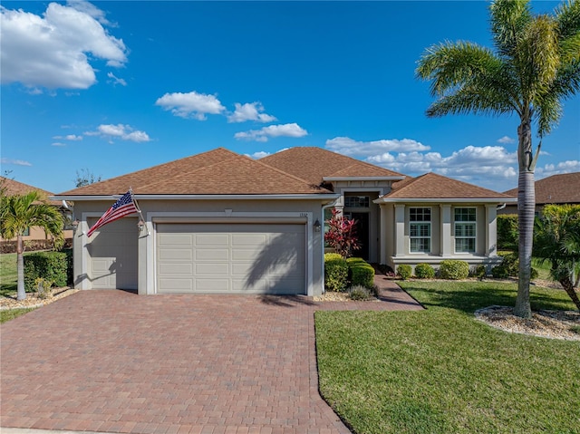 view of front of home with a front lawn, decorative driveway, an attached garage, and stucco siding