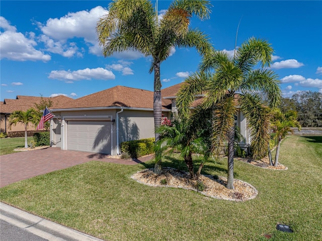 view of front of property with decorative driveway, an attached garage, a front yard, and stucco siding