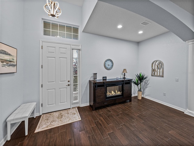 entryway with baseboards, visible vents, arched walkways, a glass covered fireplace, and wood finished floors