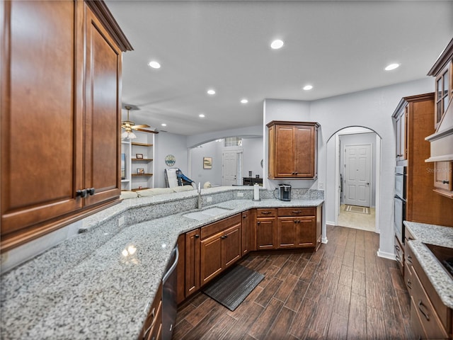 kitchen featuring arched walkways, a ceiling fan, dark wood-style floors, appliances with stainless steel finishes, and a sink