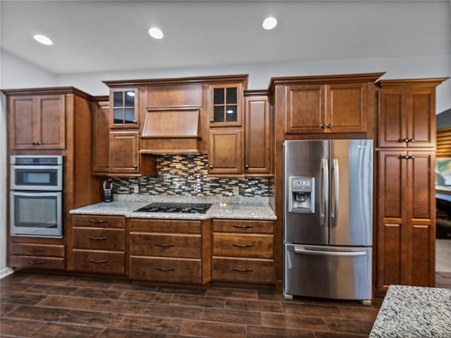 kitchen with premium range hood, appliances with stainless steel finishes, tasteful backsplash, and wood finish floors