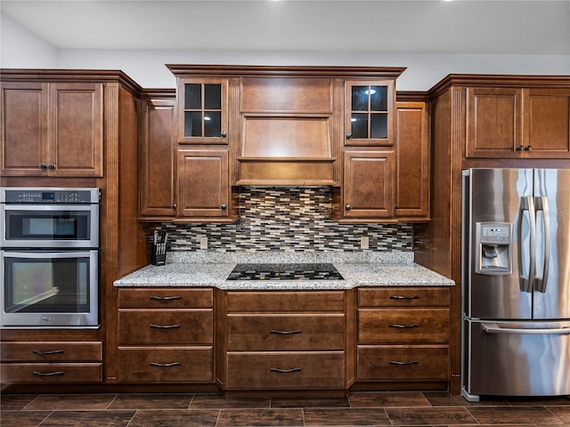 kitchen with stainless steel appliances, wood tiled floor, glass insert cabinets, and backsplash