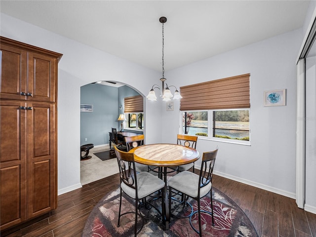 dining area featuring arched walkways, dark wood-style flooring, baseboards, and an inviting chandelier