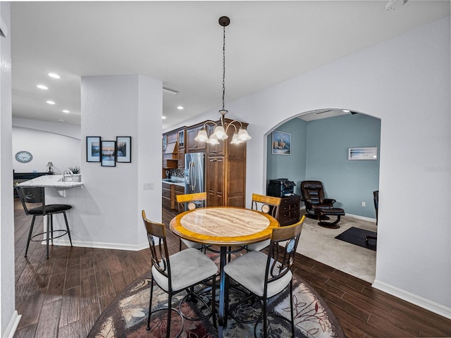 dining area with arched walkways, dark wood-type flooring, recessed lighting, and baseboards