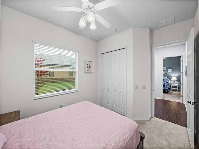 carpeted bedroom with a closet, visible vents, ceiling fan, and baseboards