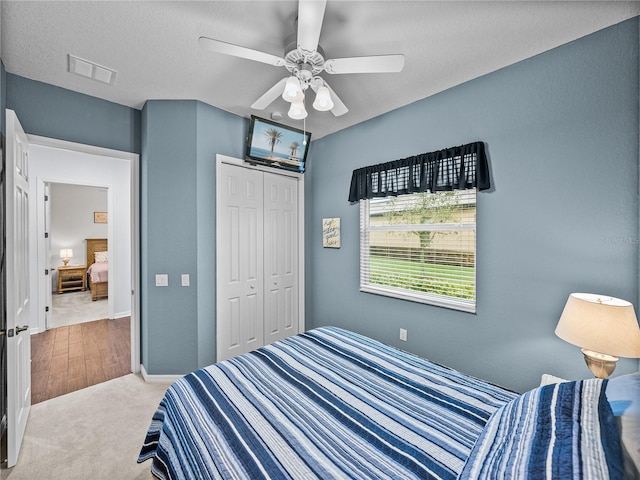 carpeted bedroom featuring a closet, visible vents, and a ceiling fan