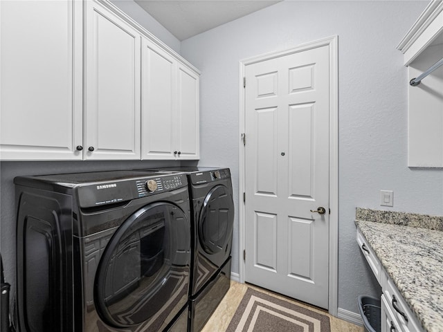 laundry area featuring separate washer and dryer, cabinet space, and baseboards